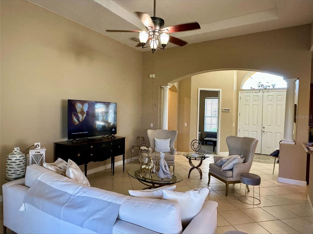 A living room features a white sofa, two armchairs, a television, and a ceiling fan — 137 MEDICI TERRACE, NORTH VENICE, FL