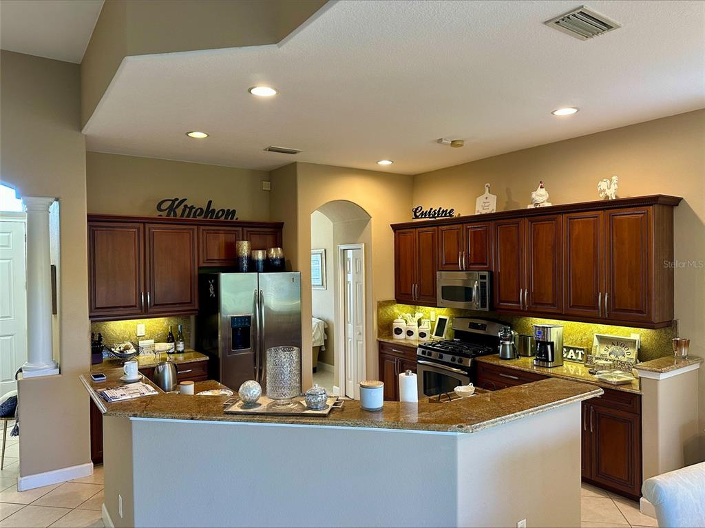 A kitchen features dark wood cabinets, granite countertops, stainless steel appliances, and recessed lighting — 137 MEDICI TERRACE, NORTH VENICE, FL