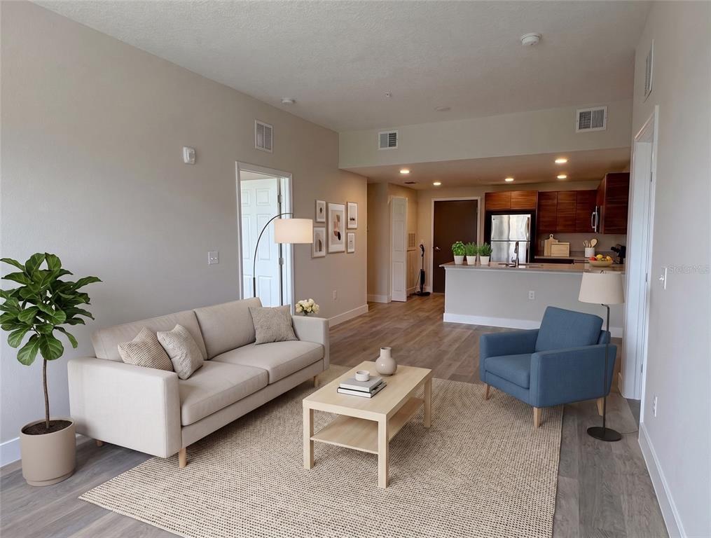 A living room with a beige sofa, blue armchair, and coffee table opens to a kitchen — 4424 S TEXAS AVENUE UNIT 1-118, ORLANDO, FL