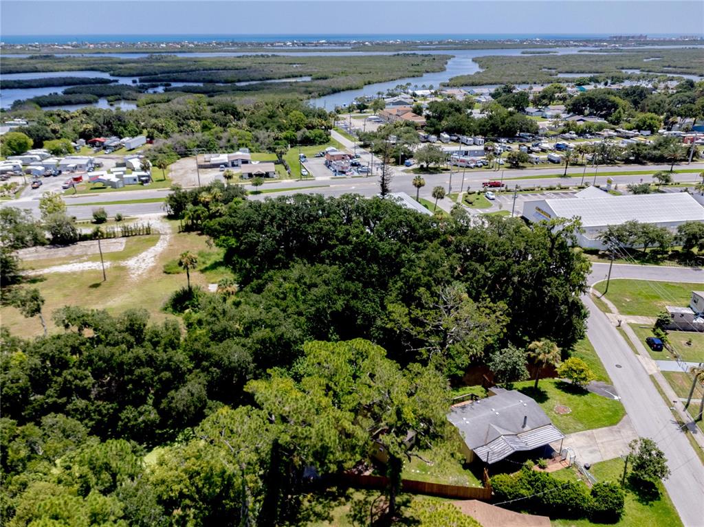 An aerial view shows a house surrounded by dense trees near a road and waterway — 120 NIVER STREET, PORT ORANGE, FL