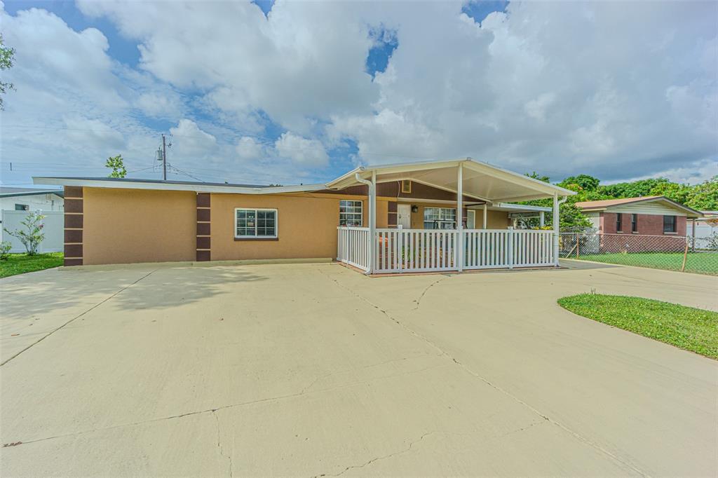 A single-story house with a large concrete driveway, a covered porch, and white railings — 4536 W IDLEWILD AVENUE, TAMPA, FL