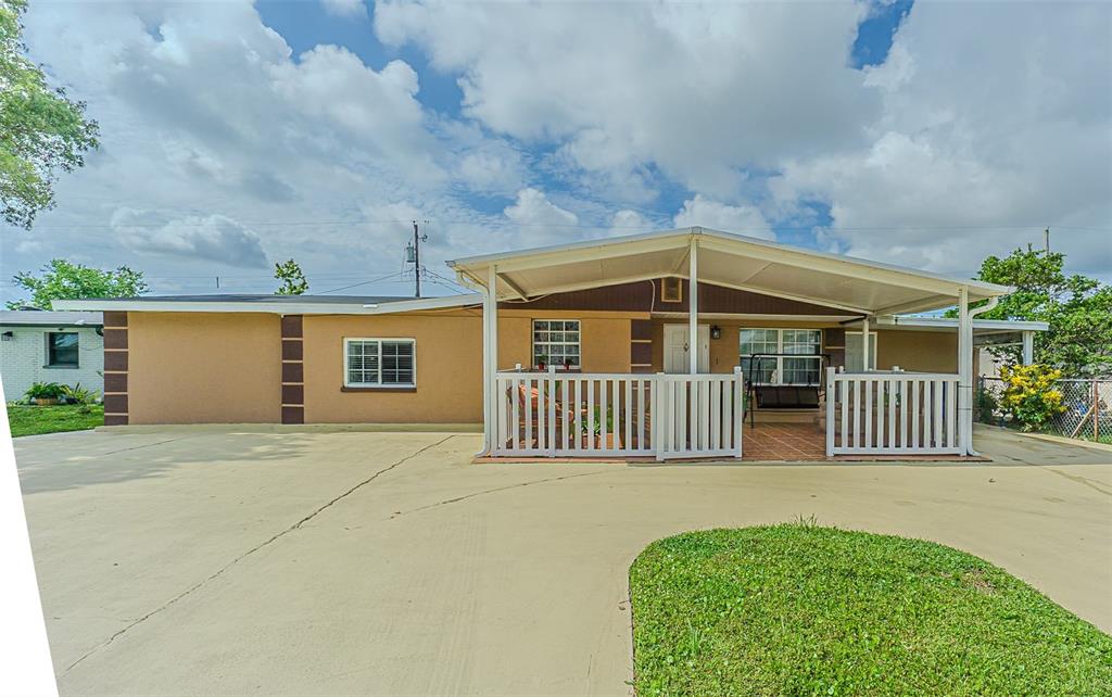 A single-story house with a tan stucco exterior, a covered front porch, and a concrete driveway — 4536 W IDLEWILD AVENUE, TAMPA, FL