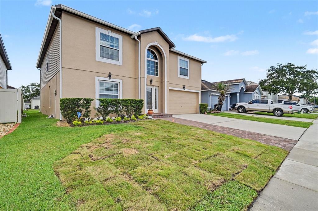 A two-story suburban house with a tan stucco exterior, arched entryway, and attached garage — 121 MAYFIELD DRIVE, SANFORD, FL