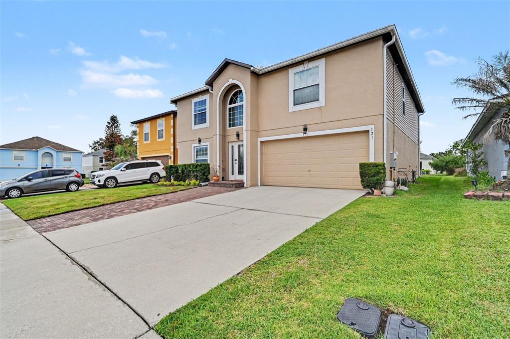 A two-story suburban house with a tan stucco exterior and a two-car garage — 121 MAYFIELD DRIVE, SANFORD, FL