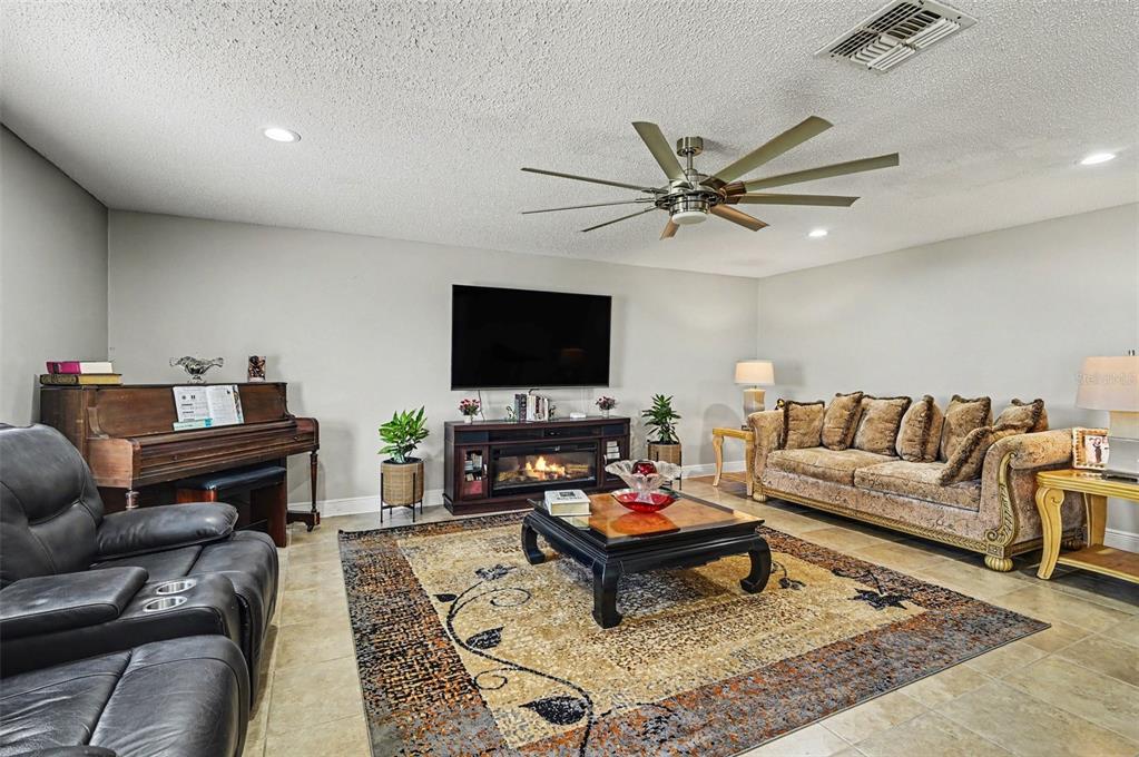 A living room features a fireplace, a large area rug, a sofa, and a piano — 121 MAYFIELD DRIVE, SANFORD, FL