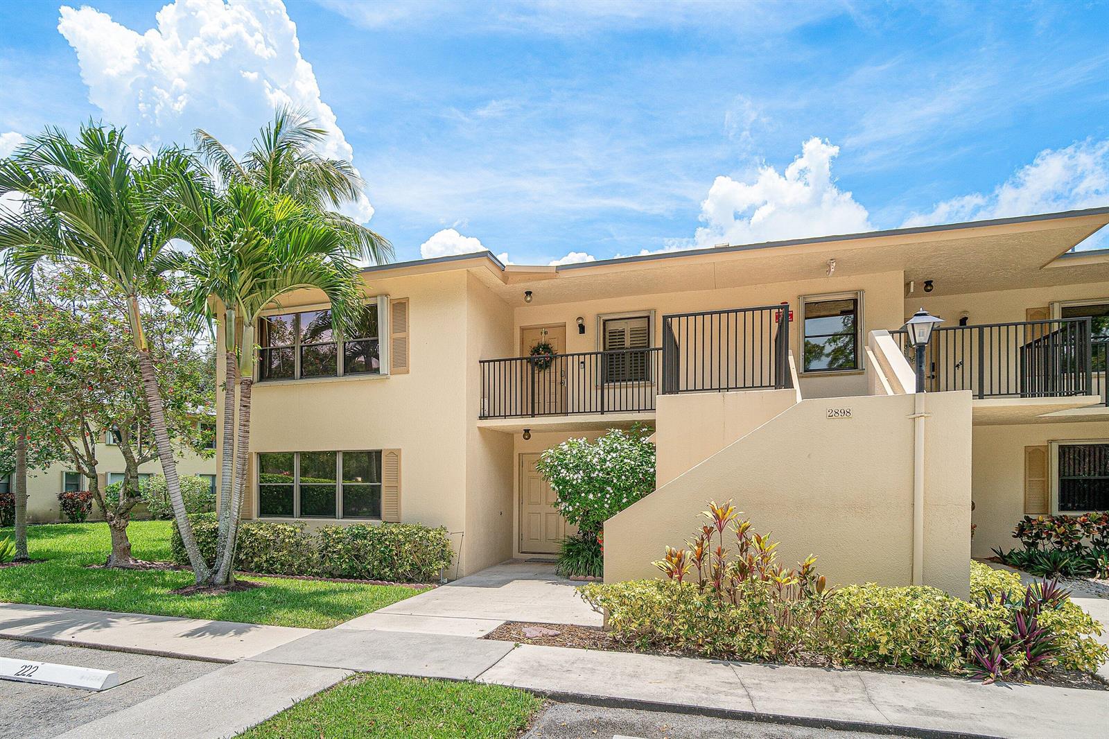 A two-story tan apartment building with a balcony, exterior stairs, and palm trees — 2898 SW 22nd Circle # 232a, Delray Beach FL 33445, DELRAY BEACH, FL