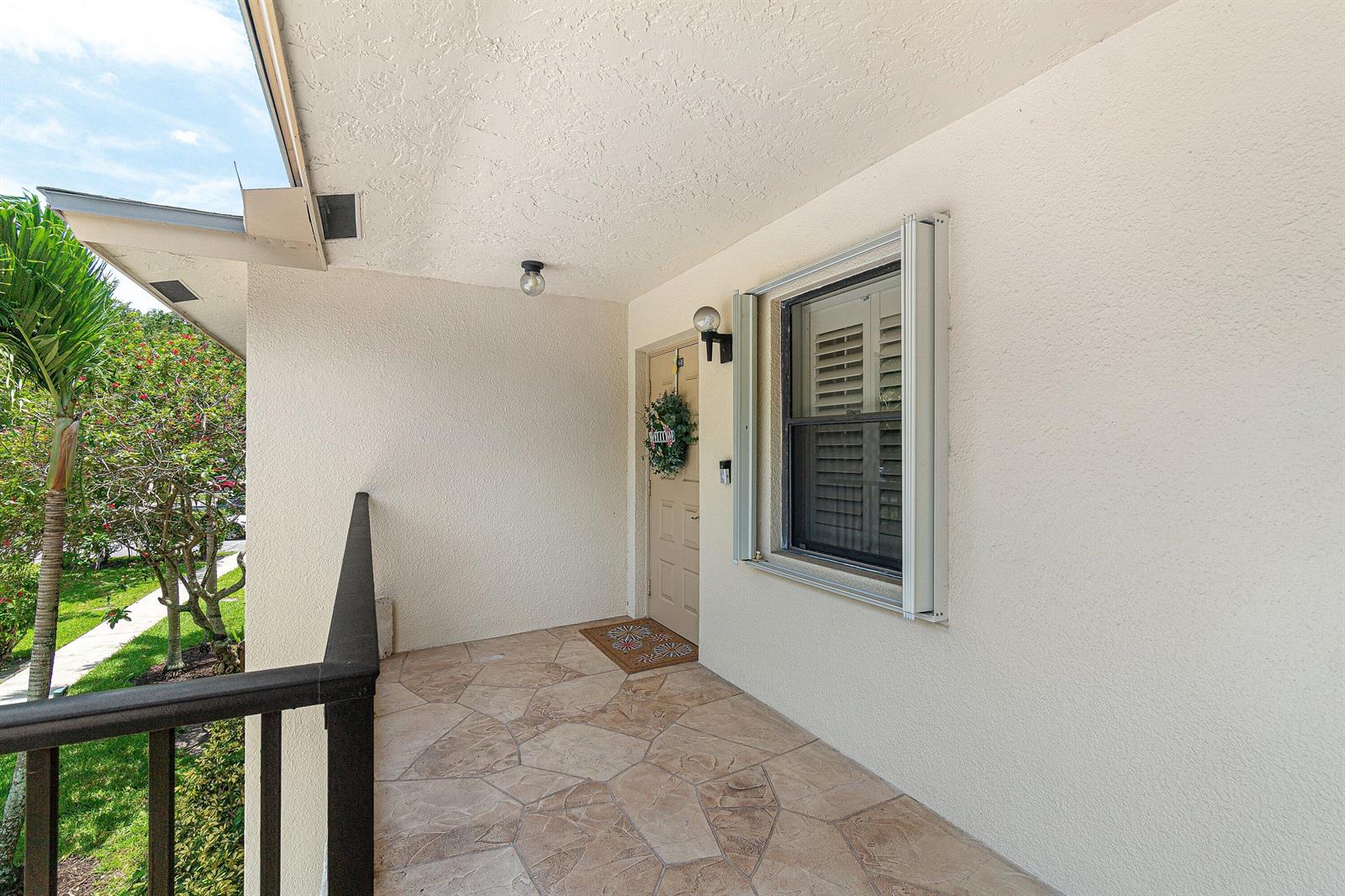 A covered entryway features a tiled floor, a beige door with a wreath, and a window — 2898 SW 22nd Circle # 232a, Delray Beach FL 33445, DELRAY BEACH, FL