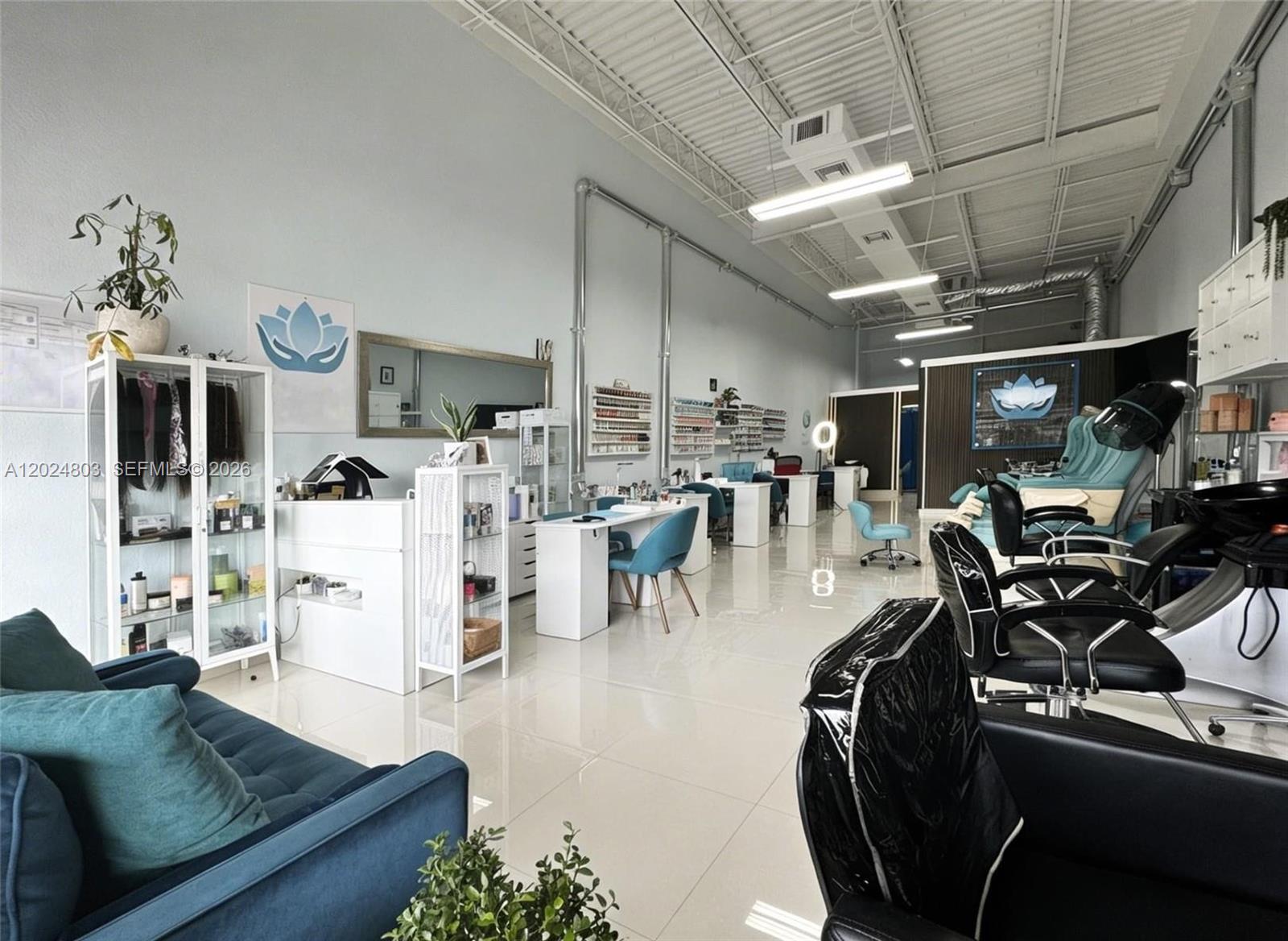 A bright, open-concept salon features white tile floors, multiple styling stations, and a waiting area — TAMARAC, FL