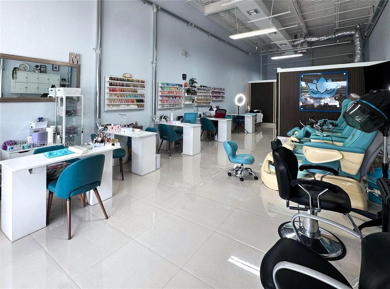 A bright nail salon features multiple manicure stations, pedicure chairs, and wall-mounted polish displays — TAMARAC, FL