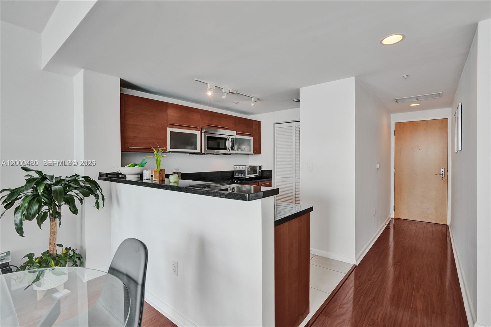 A kitchen with dark wood cabinets and black countertops overlooks a dining area — 253 NE 2nd St # 3304, Miami FL 33132, MIAMI, FL