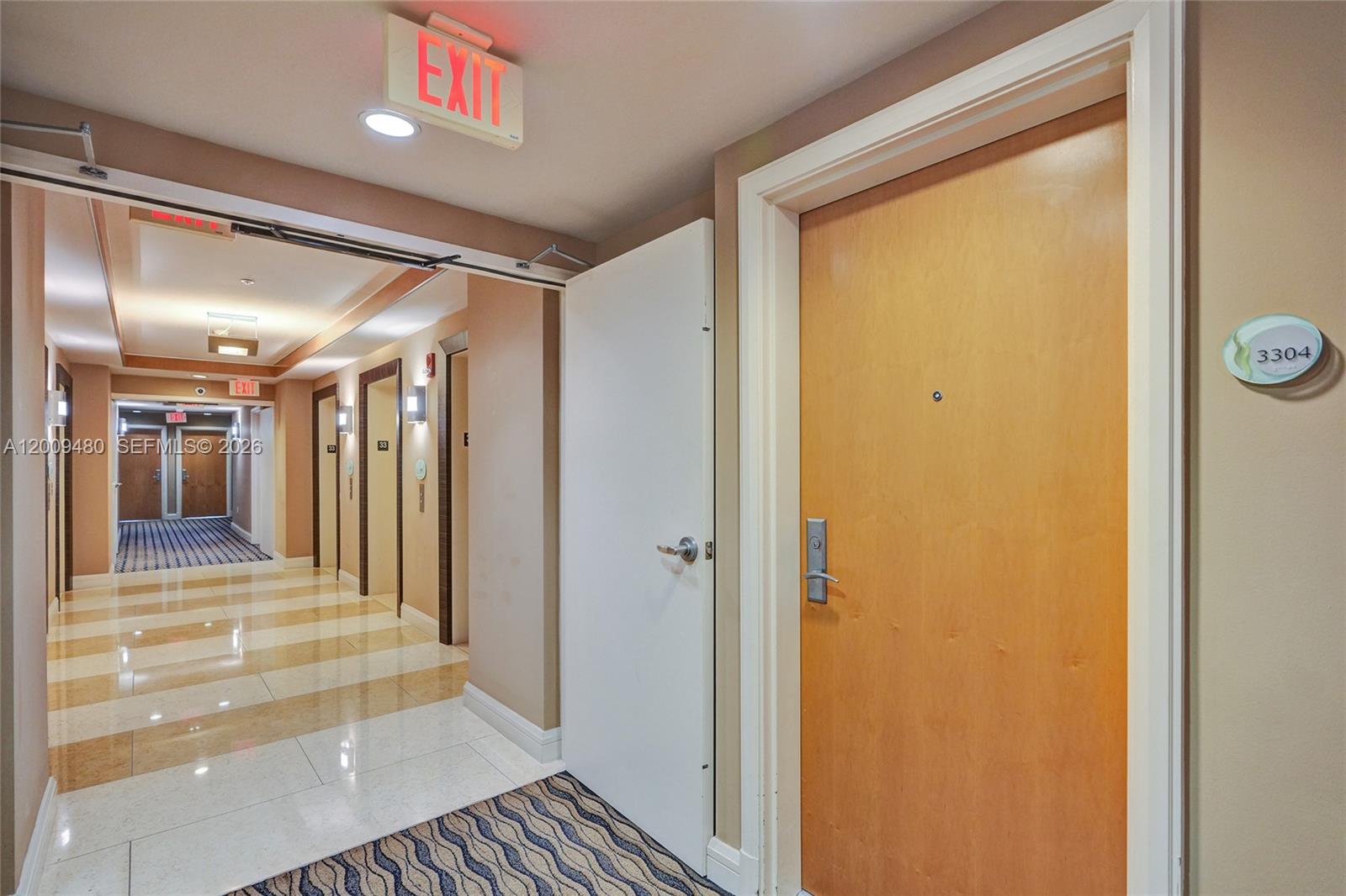A hallway with a wooden door labeled 3304 and a view into a corridor — 253 NE 2nd St # 3304, Miami FL 33132, MIAMI, FL