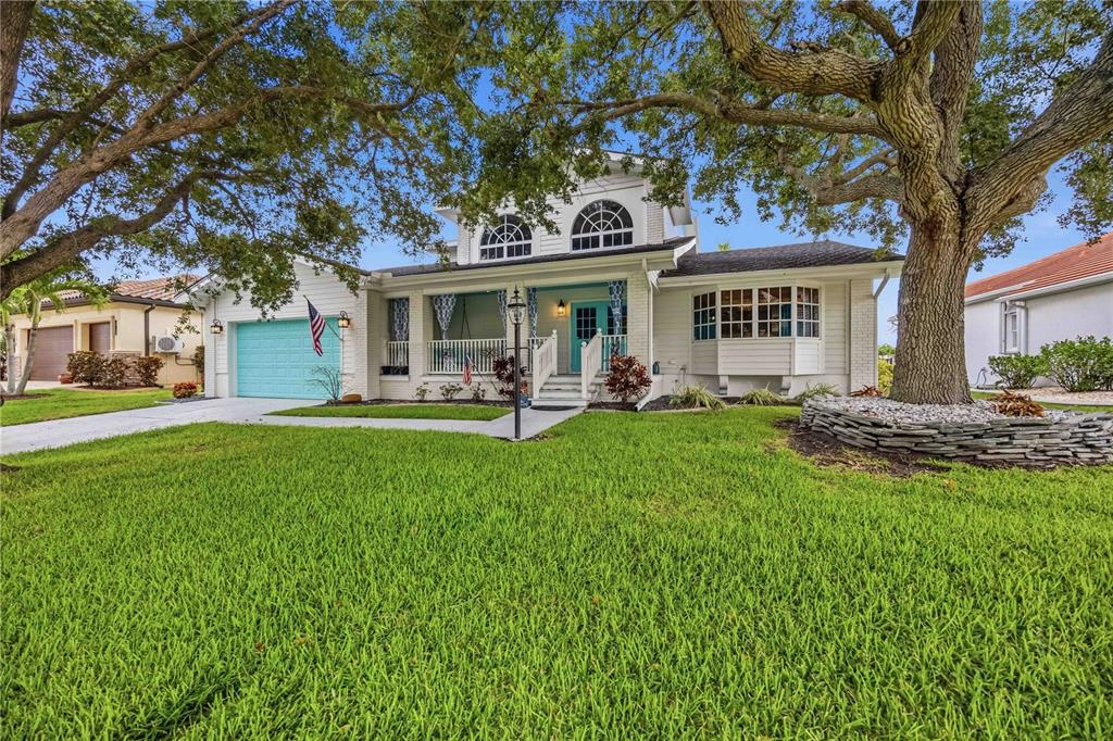 A white two-story house with a turquoise garage door and a large front oak tree — 340 PORTOFINO DRIVE, PUNTA GORDA, FL