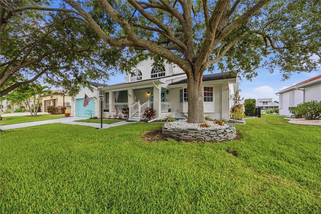 A two-story house with a large tree in the front yard and a stone planter — 340 PORTOFINO DRIVE, PUNTA GORDA, FL