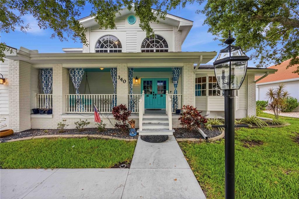 A white brick house features a front porch with a turquoise door and arched windows — 340 PORTOFINO DRIVE, PUNTA GORDA, FL