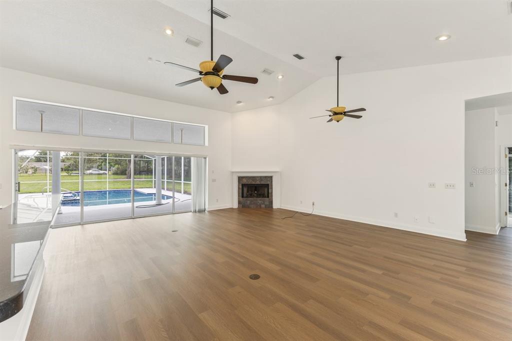 A spacious living room features wood flooring, a fireplace, two ceiling fans, and sliding glass doors — 12001 LAKE BUTLER BOULEVARD, WINDERMERE, FL