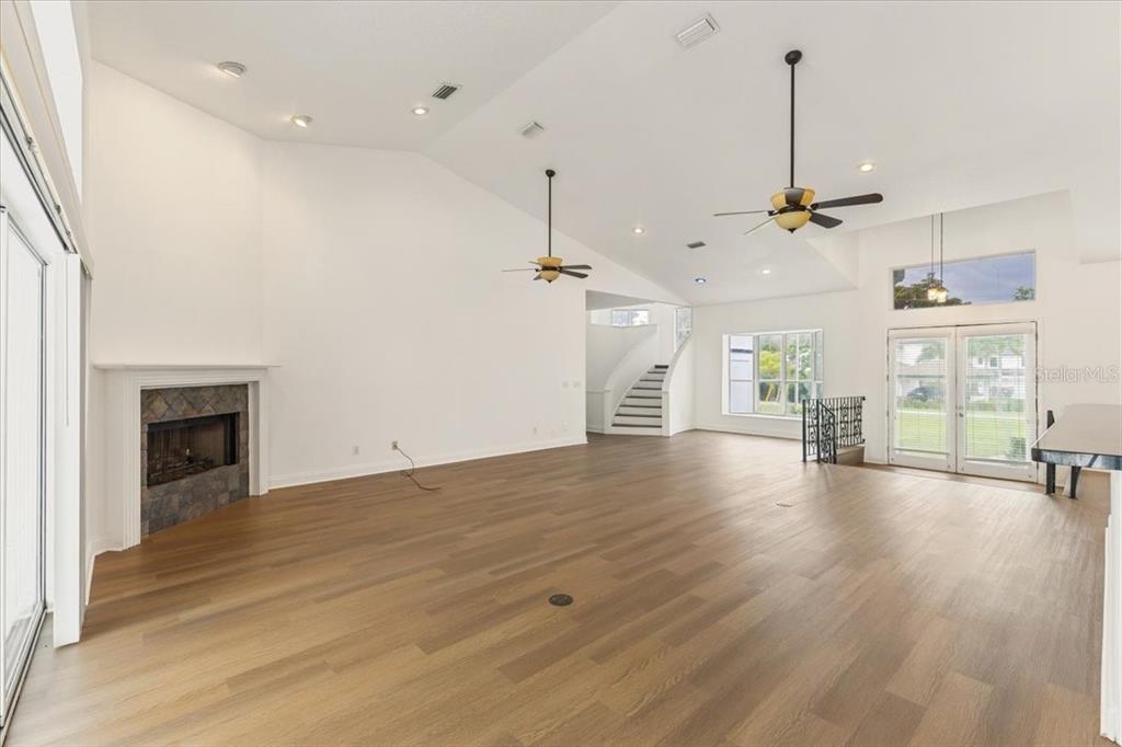A spacious living room features vaulted ceilings, hardwood floors, a stone fireplace, and a staircase — 12001 LAKE BUTLER BOULEVARD, WINDERMERE, FL