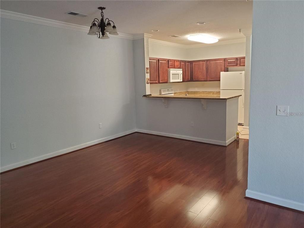 A dining area with wood flooring opens to a kitchen with dark wood cabinets — 1371 TUSCAN TER UNIT 3307, DAVENPORT, FL
