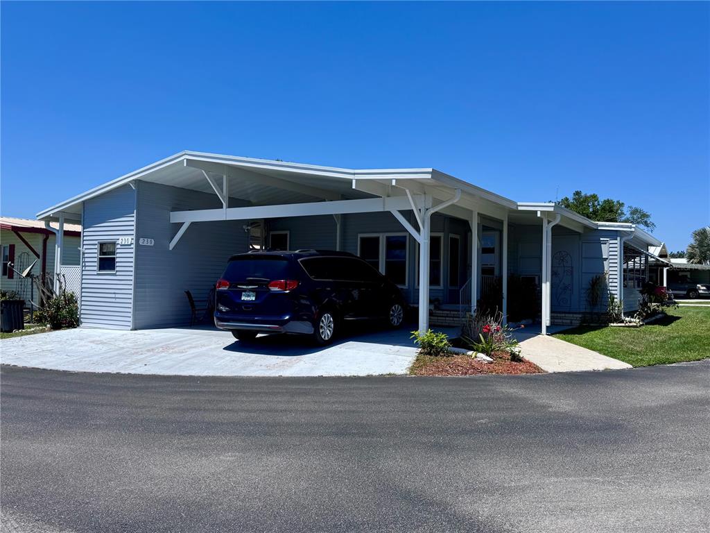 A light blue manufactured home features a large carport and a concrete driveway — 2055 S FLORAL AVENUE UNIT 230, BARTOW, FL