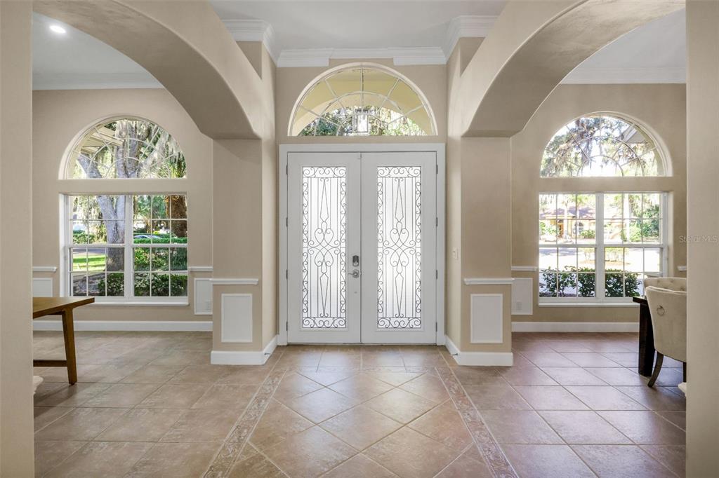 An entryway with tile floors, double glass-paneled doors, and arched windows on both sides — 11 CYPRESS HOLLOW LANE, ORMOND BEACH, FL
