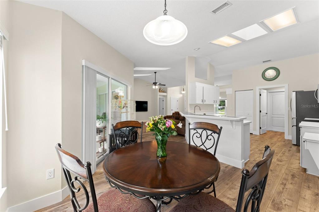 A dining area with a round wooden table, chairs, and an open kitchen in the background — 846 MARLEY DRIVE, PORT ORANGE, FL