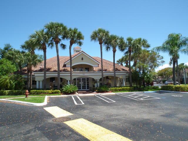 A low-rise building with a tiled roof is surrounded by palm trees and a parking lot — 815 W Boynton Beach Boulevard # 204, Boynton Beach FL 33426, BOYNTON BEACH, FL