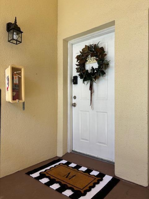A white front door with a wreath and a fire extinguisher mounted on the wall — 815 W Boynton Beach Boulevard # 204, Boynton Beach FL 33426, BOYNTON BEACH, FL