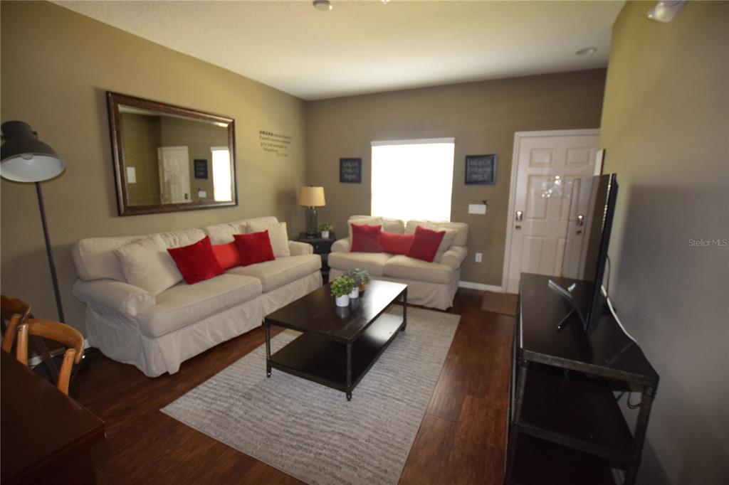 A living room features two beige sofas, a dark coffee table, and wood-look flooring — 3222 WISH AVENUE, KISSIMMEE, FL