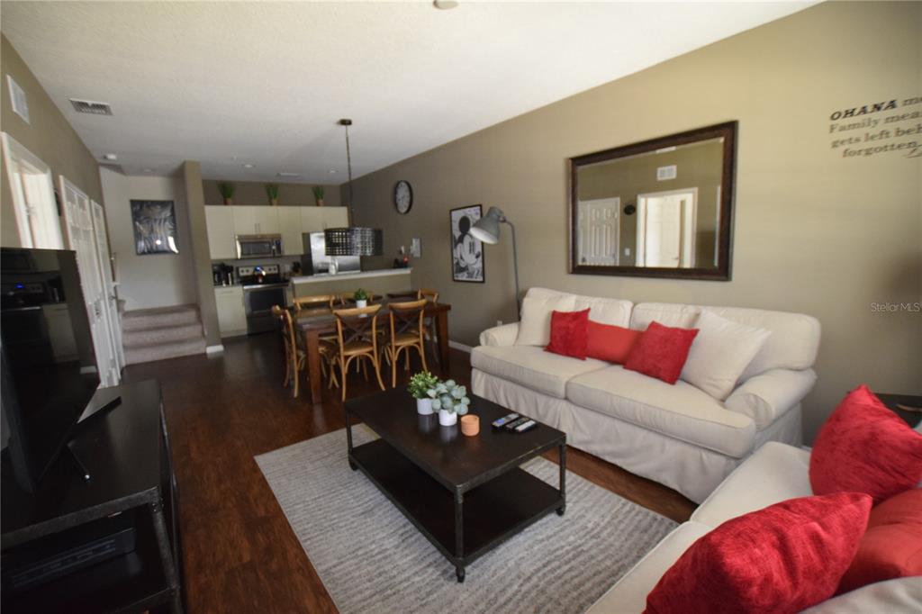 A living room and dining area with hardwood floors, a white sofa, and kitchen access — 3222 WISH AVENUE, KISSIMMEE, FL