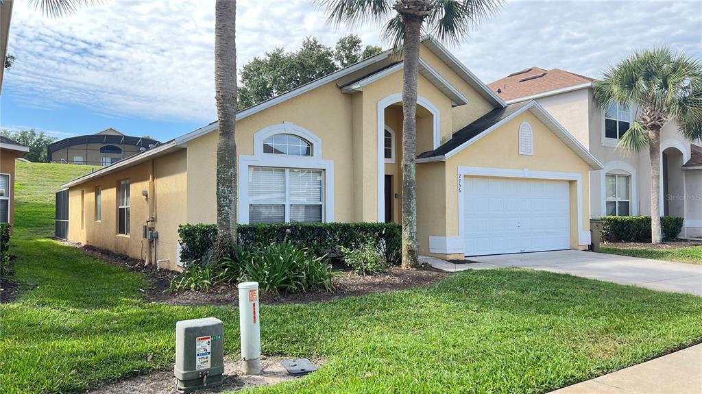 A yellow single-story house with a two-car garage and palm trees in the front yard — 2756 LIDO KEY DRIVE, KISSIMMEE, FL