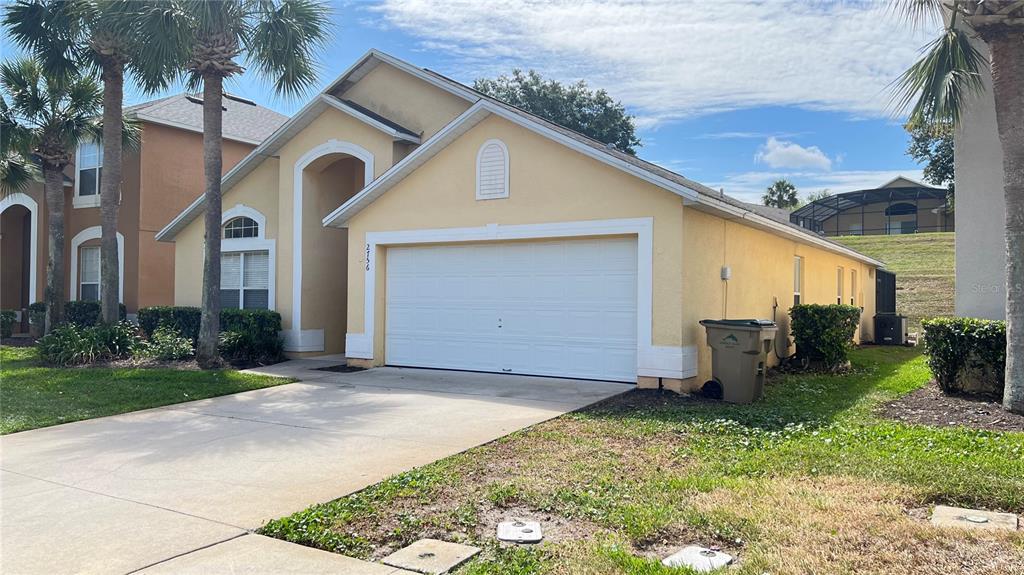 A single-story yellow house with a two-car garage and palm trees in the front yard — 2756 LIDO KEY DRIVE, KISSIMMEE, FL