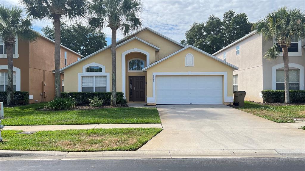 A single-story yellow house with a two-car garage and palm trees in the front yard — 2756 LIDO KEY DRIVE, KISSIMMEE, FL