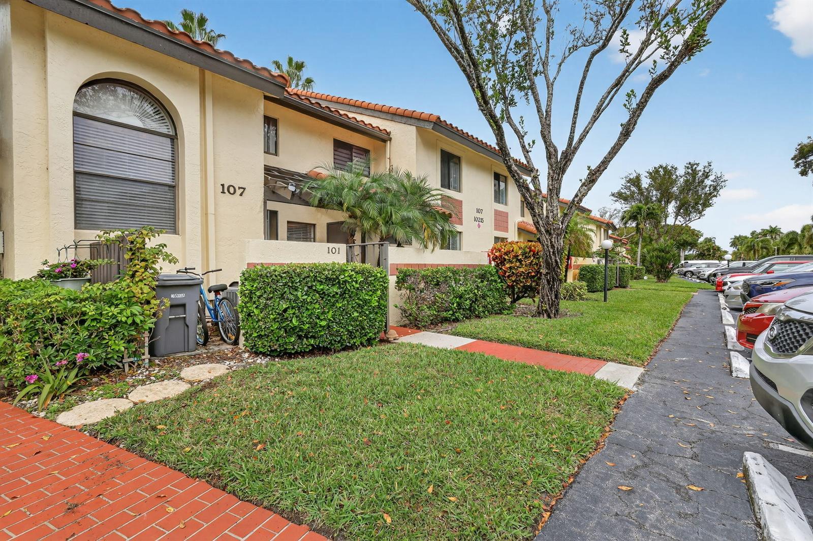 An exterior view of a two-story apartment building with a parking lot and landscaping — 10215 N Circle Lake Drive # 101, Boynton Beach FL 33437, BOYNTON BEACH, FL