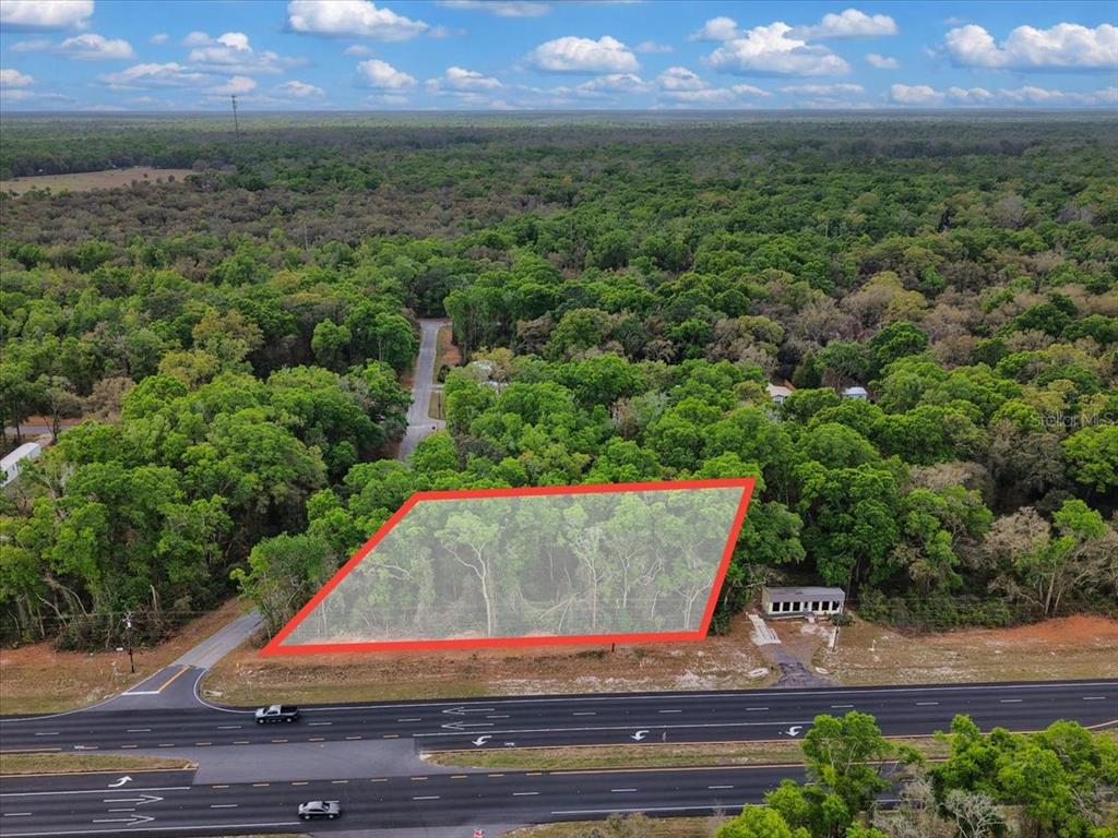 An aerial view shows a wooded, trapezoidal lot bordered by a multi-lane highway — 000 NW US HWY 19, FANNING SPRINGS, FL