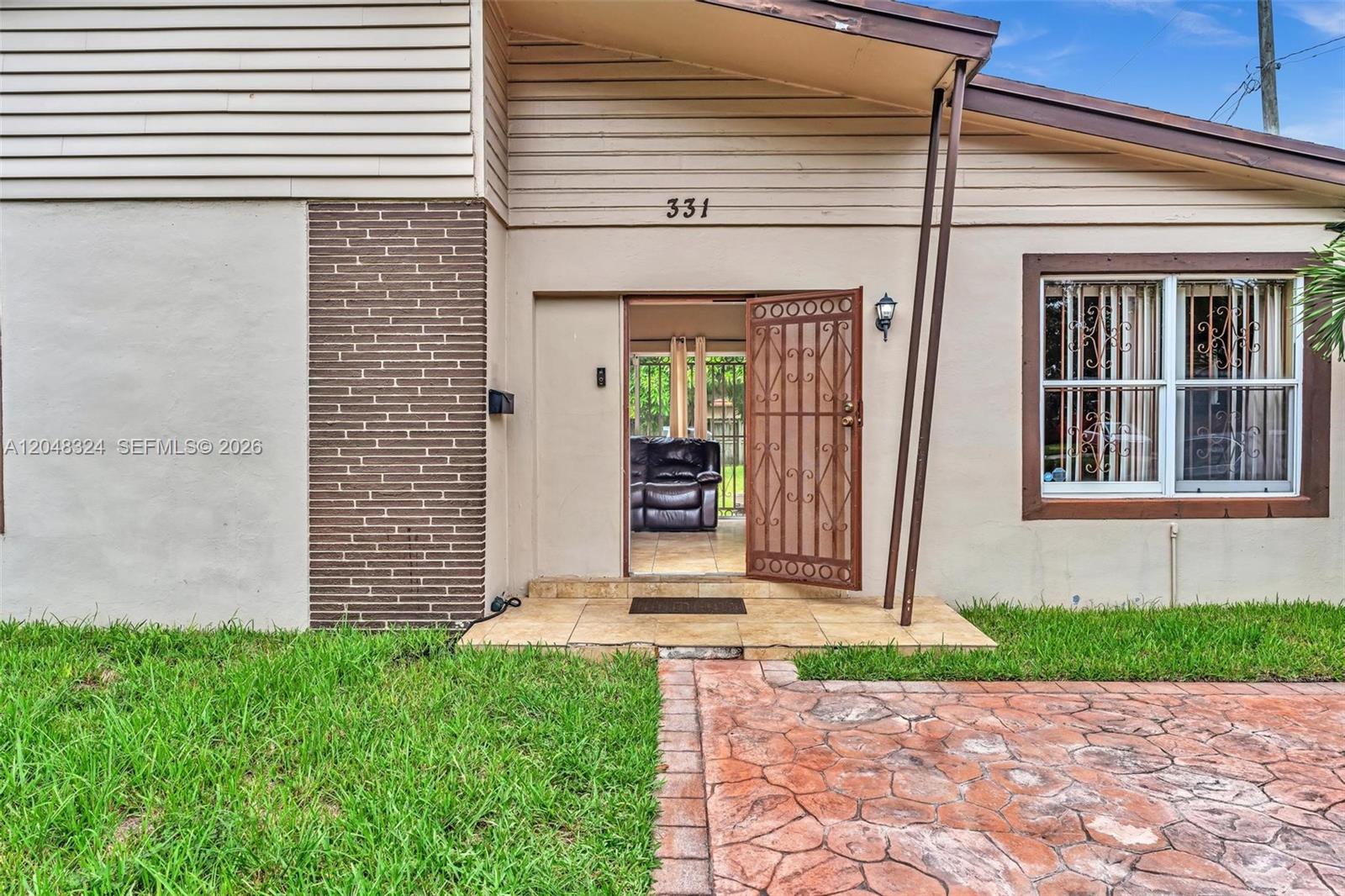 The exterior of a house features a brick accent wall, a tiled entryway, and a screen door — 331 NE 176th St, North Miami Beach FL 33162, NORTH MIAMI BEACH, FL