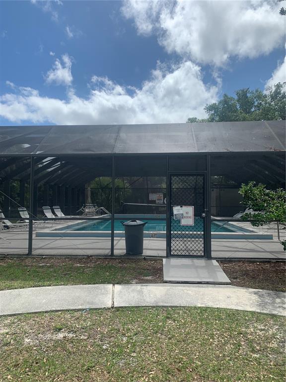 A screened-in swimming pool area with lounge chairs and a trash can — 22481 WESTCHESTER BOULEVARD UNIT B31, PUNTA GORDA, FL