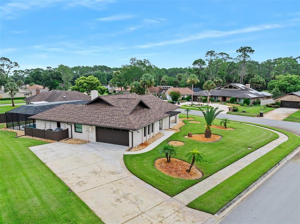 A rustic kitchen features wood cabinets, a granite-topped island with bar seating, and hardwood floors — 120 PEACHTREE CIRCLE, DAYTONA BEACH, FL