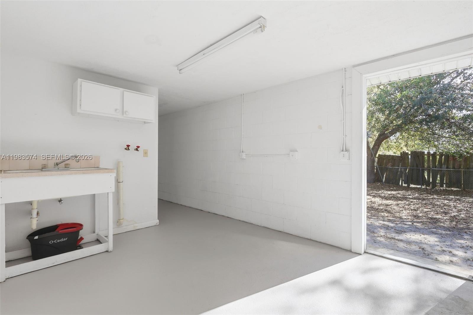 A utility room features a sink, laundry hookups, white block walls, and a door to outdoors — 2489 ADAMS AVE, Deltona FL 32738, DELTONA, FL