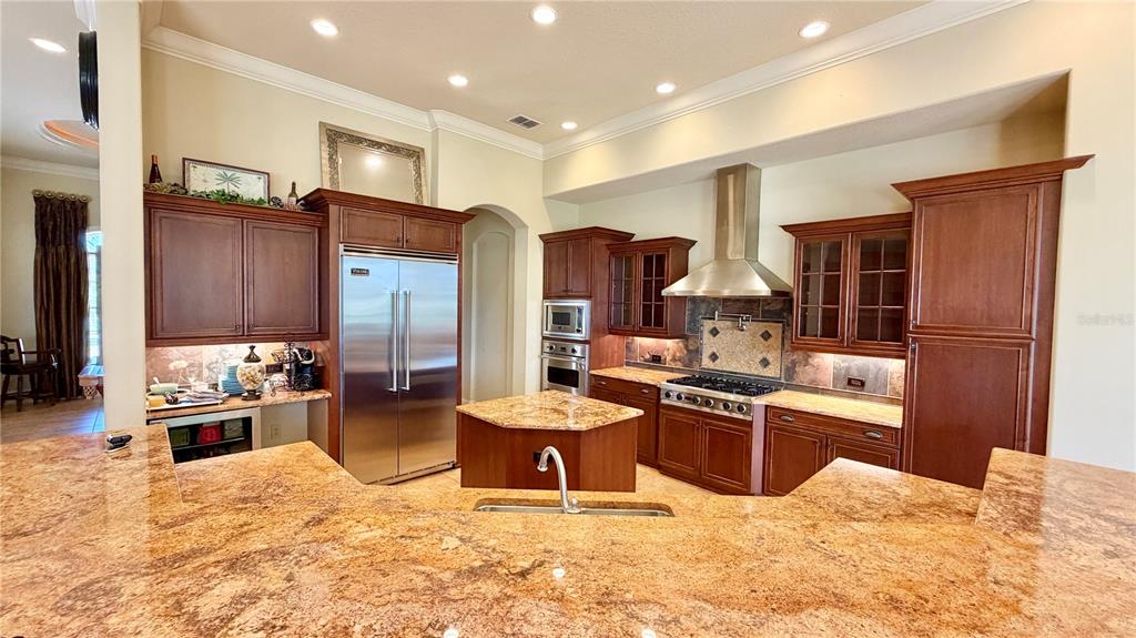 A kitchen features dark wood cabinetry, granite countertops, stainless steel appliances, and a central island — 6717 SW 179TH AVENUE ROAD, DUNNELLON, FL
