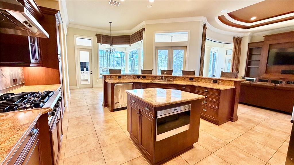 A kitchen with dark wood cabinets, granite countertops, a center island, and tile flooring — 6717 SW 179TH AVENUE ROAD, DUNNELLON, FL