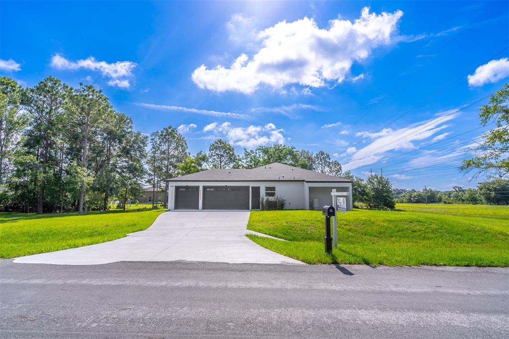 A single-story house with a two-car garage and a concrete driveway sits on a grassy lot — 2943 DECKER AVENUE, ORLANDO, FL