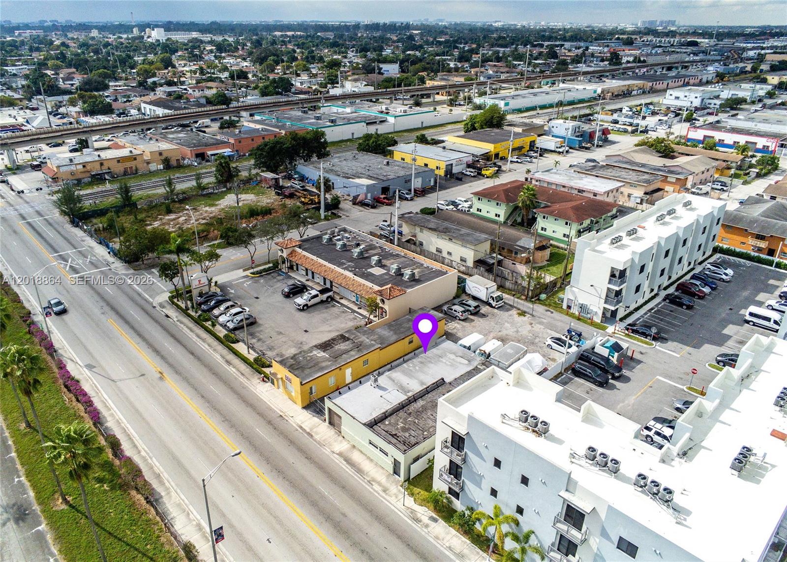 An aerial view shows commercial buildings, parking lots, and a nearby elevated railway track — 2230 Palm Ave, Hialeah FL 33010, HIALEAH, FL