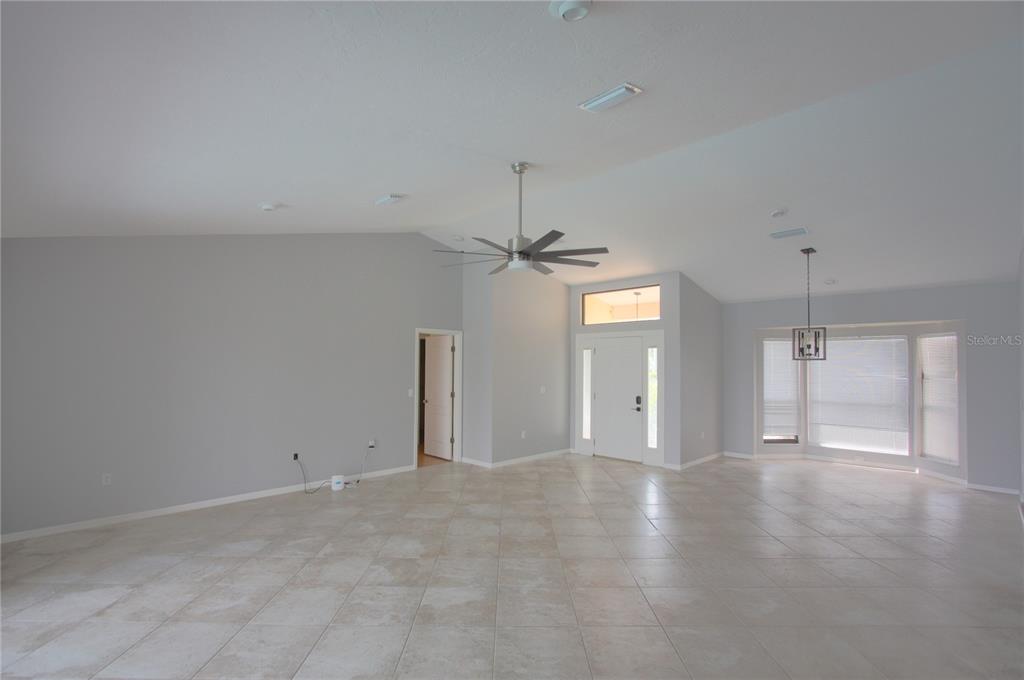 An open-concept living area features light gray walls, tile flooring, and a vaulted ceiling — 6907 RANCH ROAD, SARASOTA, FL