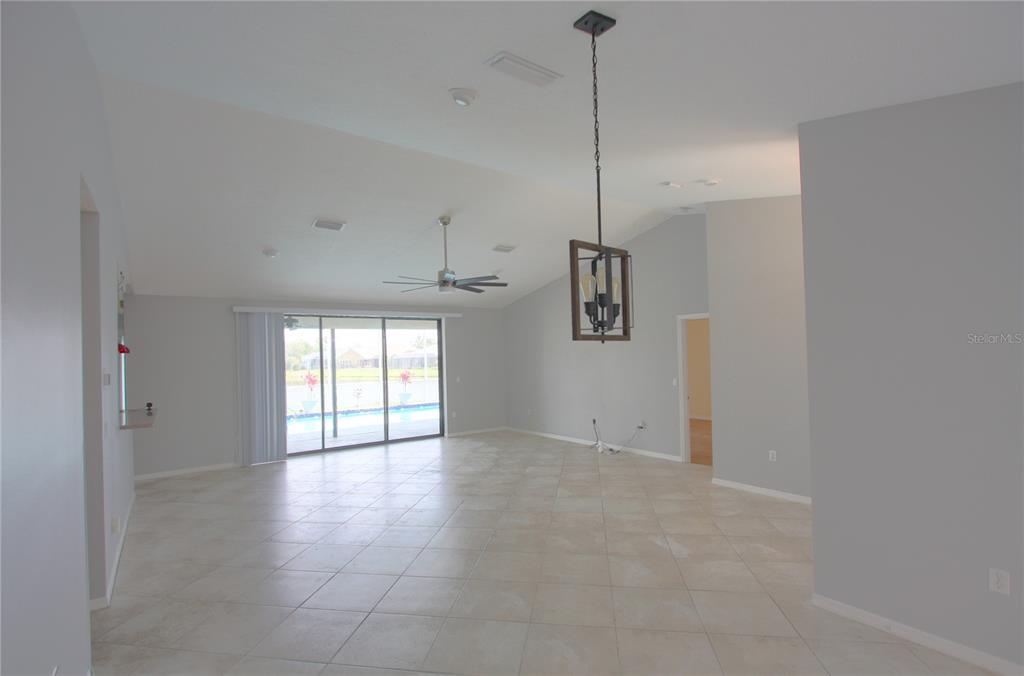 A spacious living area features light tile flooring, a vaulted ceiling, and sliding glass doors — 6907 RANCH ROAD, SARASOTA, FL