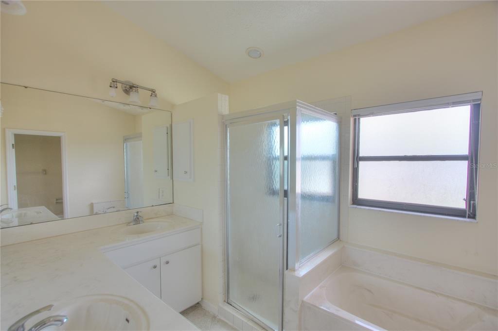 A bathroom features a double vanity, a glass-enclosed shower, and a built-in bathtub — 6907 RANCH ROAD, SARASOTA, FL