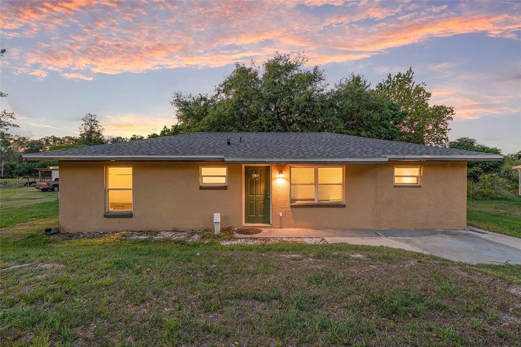 A single-story tan house with a dark green front door and a gray shingled roof — 17611 FL33, GROVELAND, FL