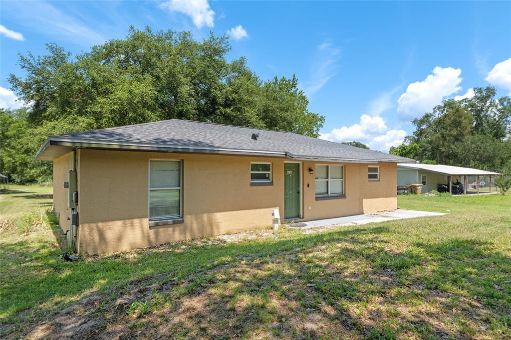 A tan, single-story house with a green door and a gray shingled roof — 17611 FL33, GROVELAND, FL