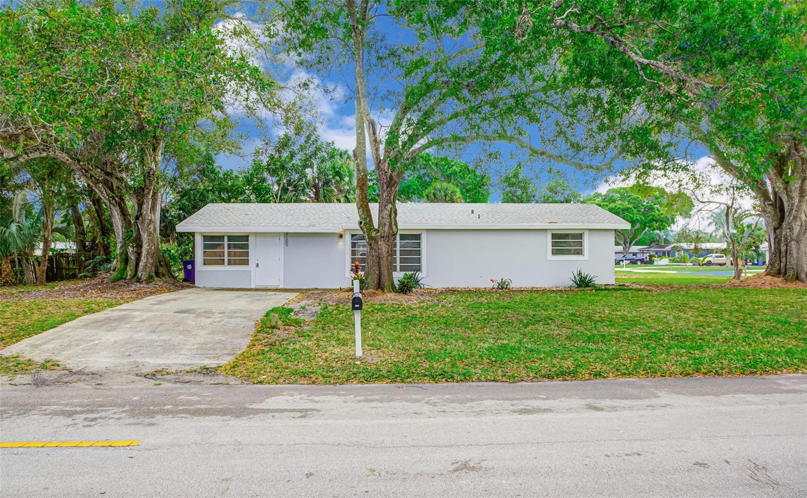 A single-story, light-gray house with a concrete driveway and large trees in the front yard — 3105 18th Street, Vero Beach FL 32960, VERO BEACH, FL
