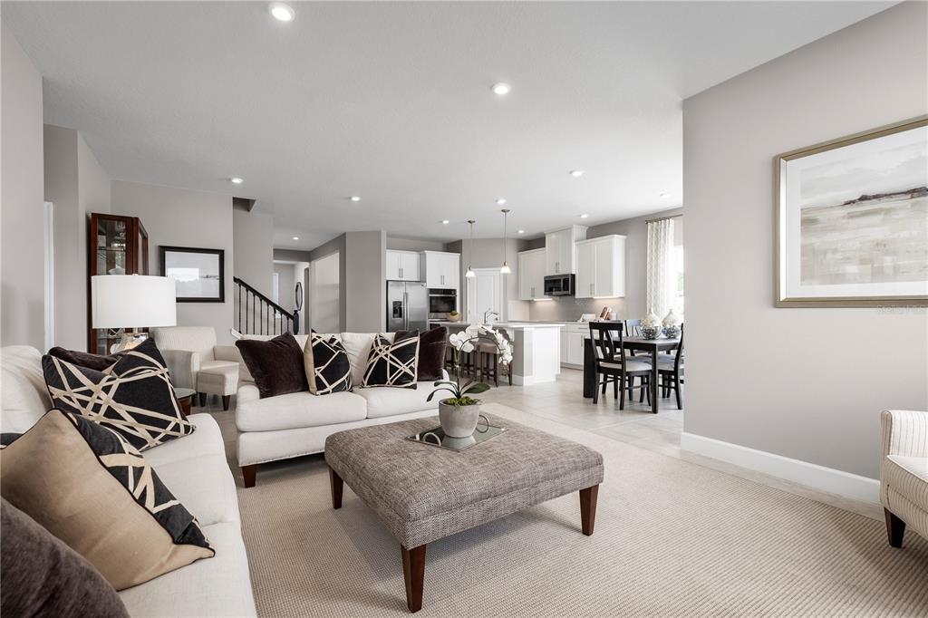 A living room with a white sofa and ottoman opens into a kitchen with white cabinets — 11149 NELLIE CROSSING CIRCLE, CLERMONT, FL