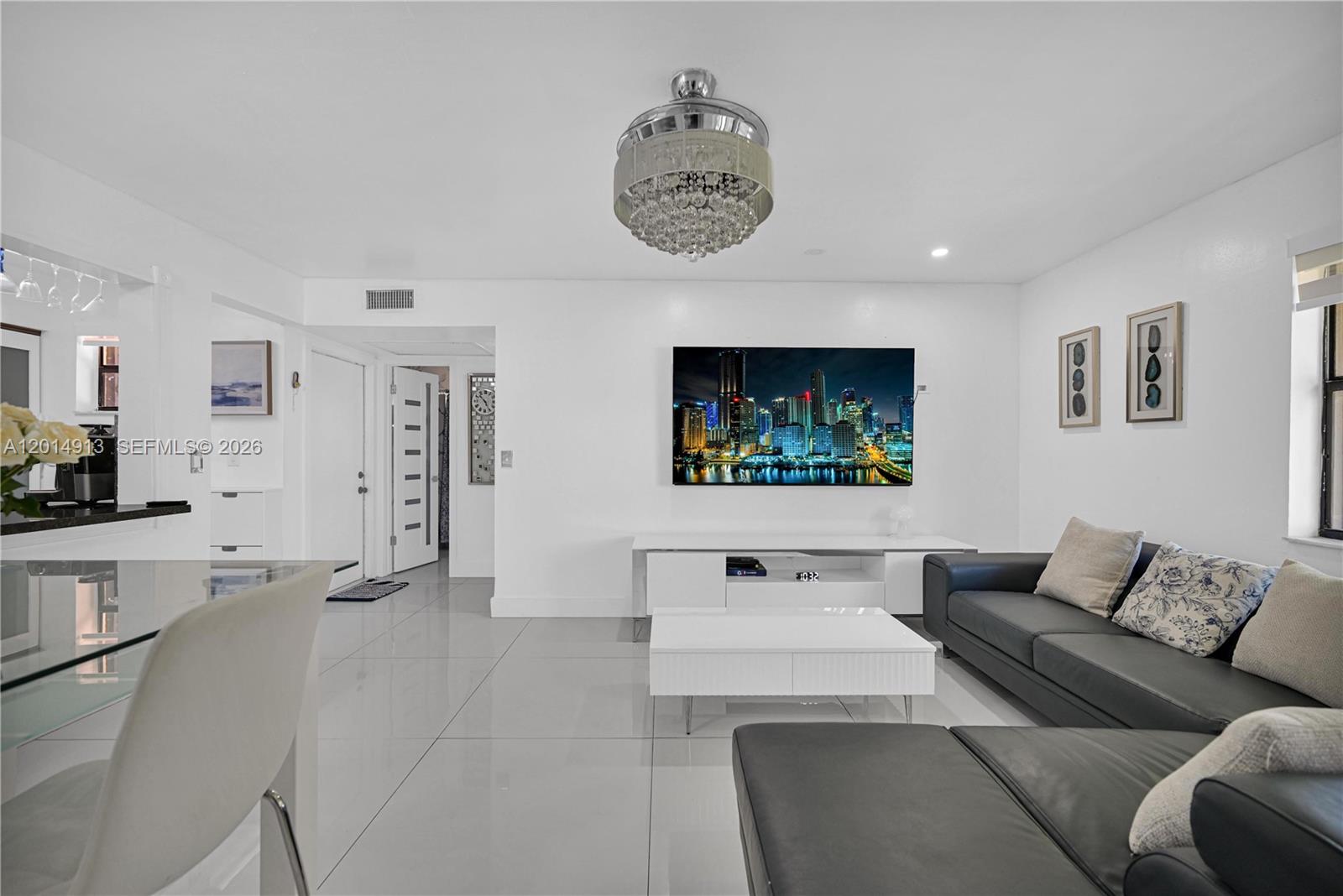 A modern living room features white tile floors, a crystal ceiling fan, and a wall-mounted television — 6535 W 26th Dr # 39, Hialeah FL 33016, HIALEAH, FL
