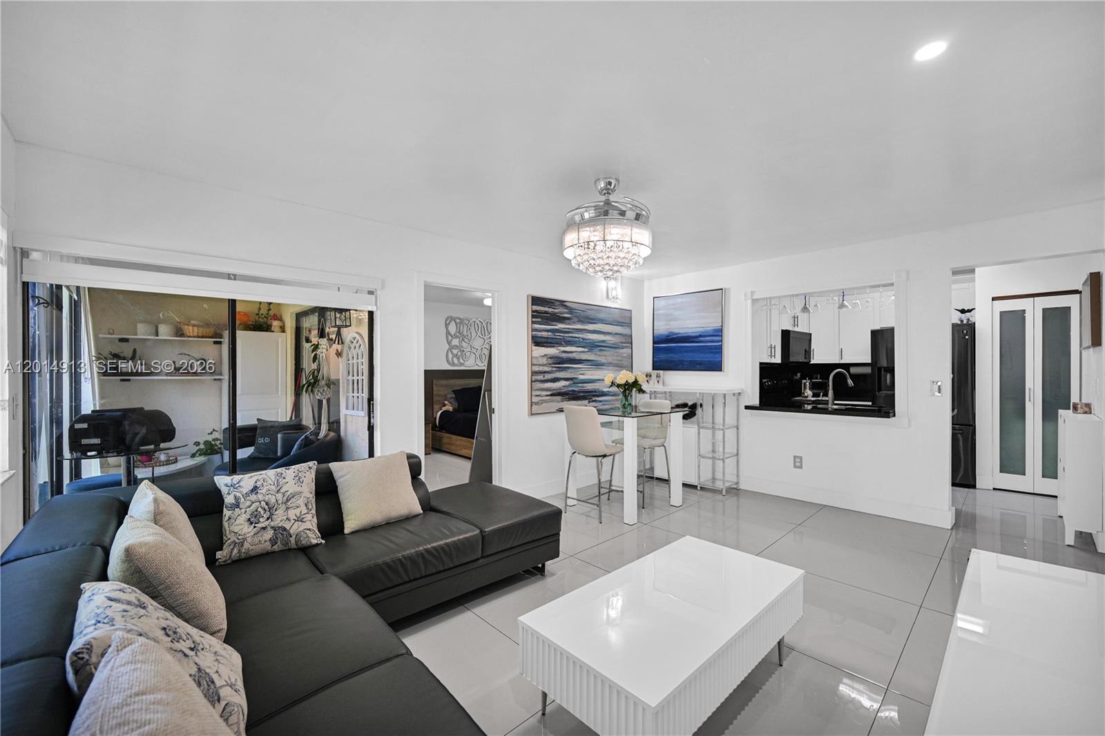 A modern living room features a black sectional sofa, white tile floors, and a dining area — 6535 W 26th Dr # 39, Hialeah FL 33016, HIALEAH, FL
